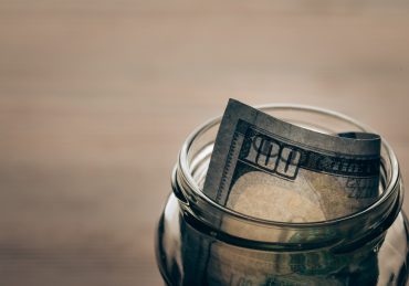 glass jar with dollar banknote on wooden tabletop